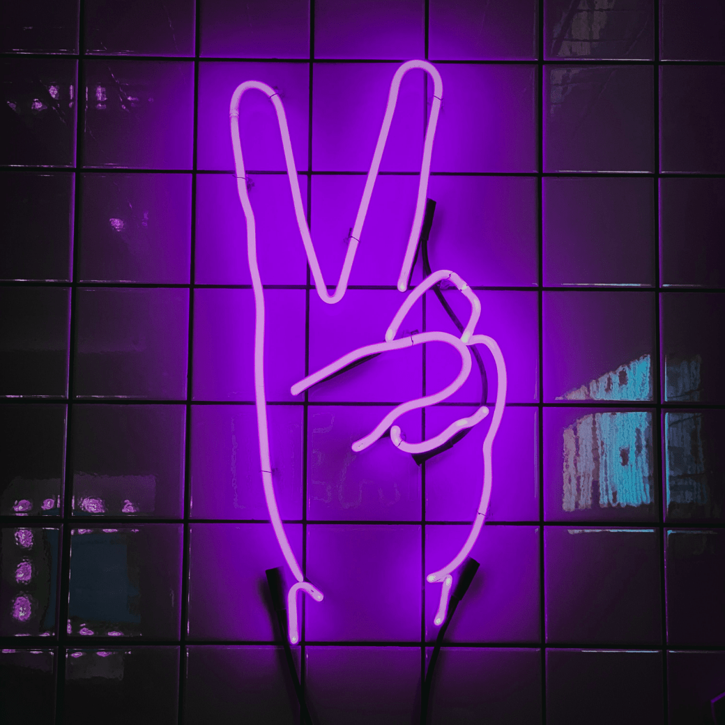A neon sign of a hand making the peace symbol.